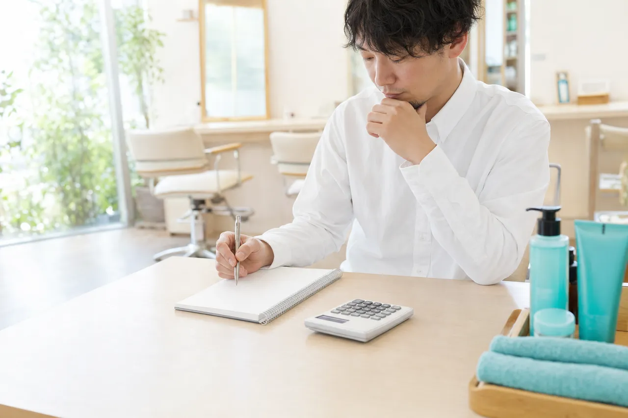 電卓とノートで売上を試算するデスク