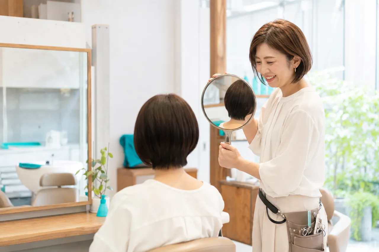 ショートボブの女性客にうなじを見せて提案する美容師