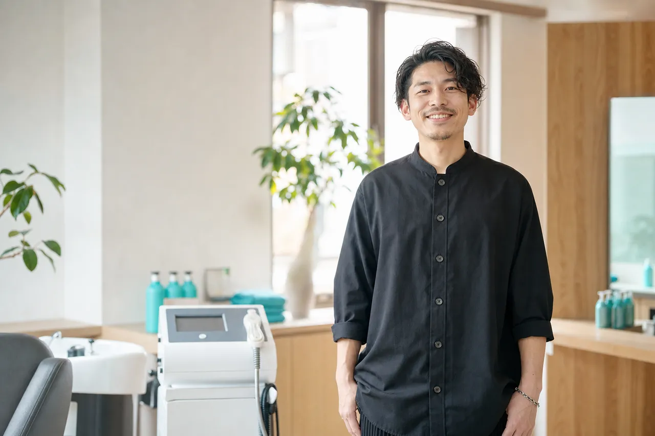 導入した機器のある明るいサロンに立つオーナー