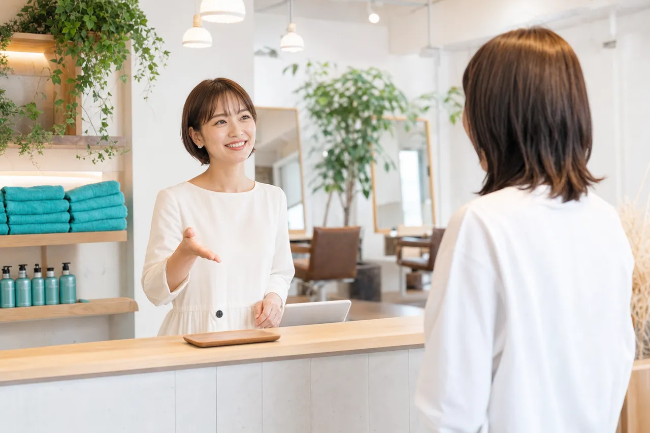 明るい美容室の受付でお客様を迎えるスタッフ